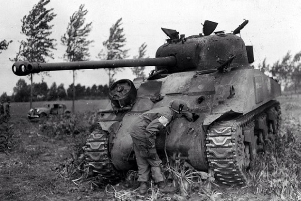 A Screaming Eagle inspects the hole a German anti-tank gun made in a British 17lb Sherman Firefly during a fierce engagement near Erp, Holland on September 23, 1945.jpg